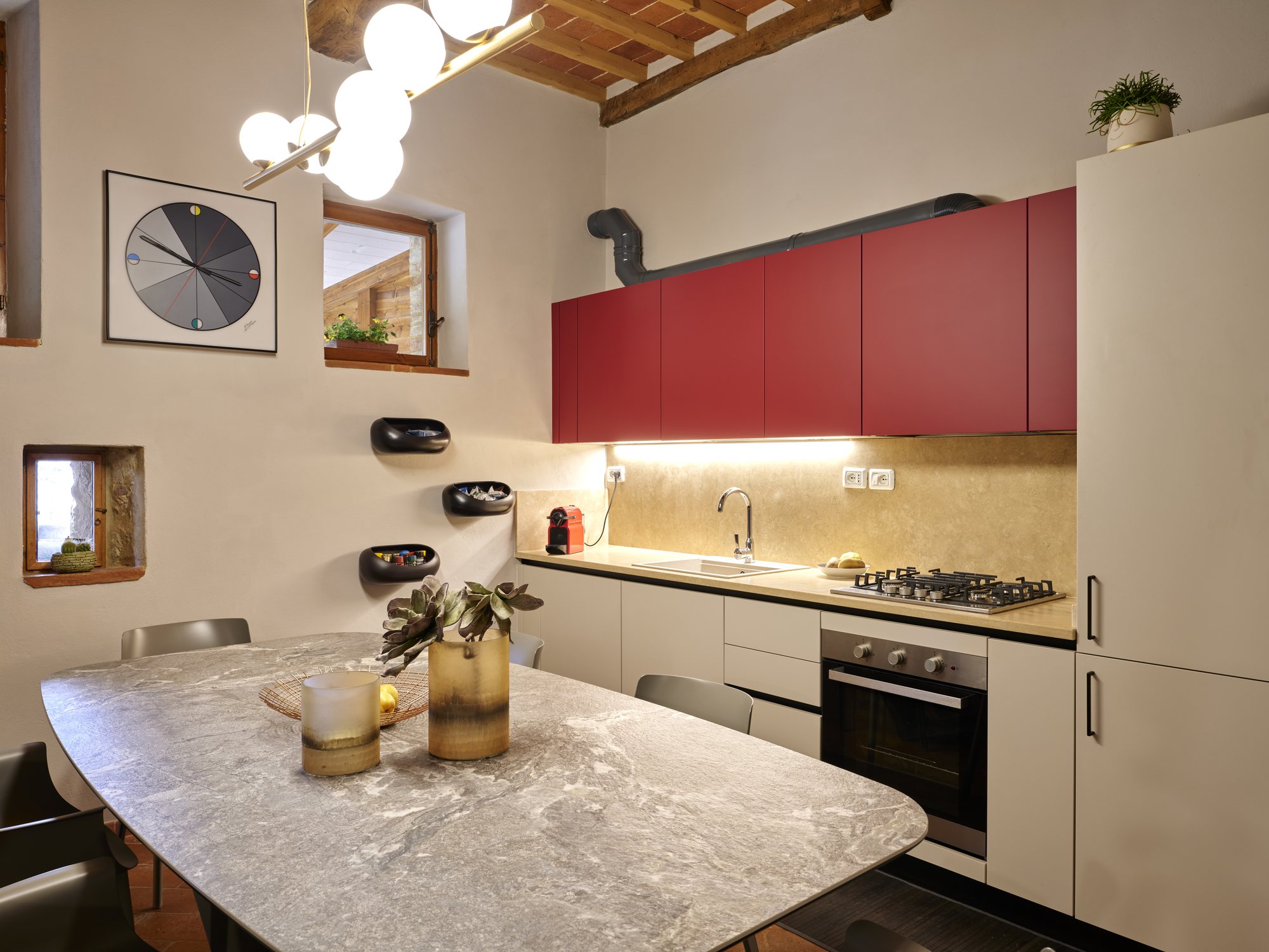 Cucina con pensili rossi e schienale in travertino retroilluminato