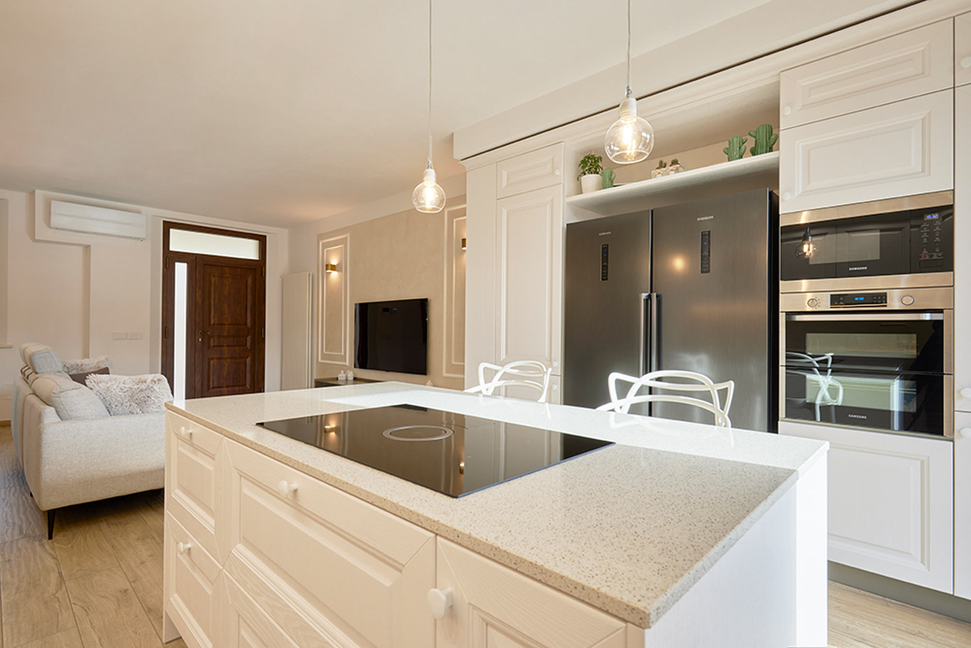 Cucina classica bianca con isola per la colazione e colonne frigo in acciaio.