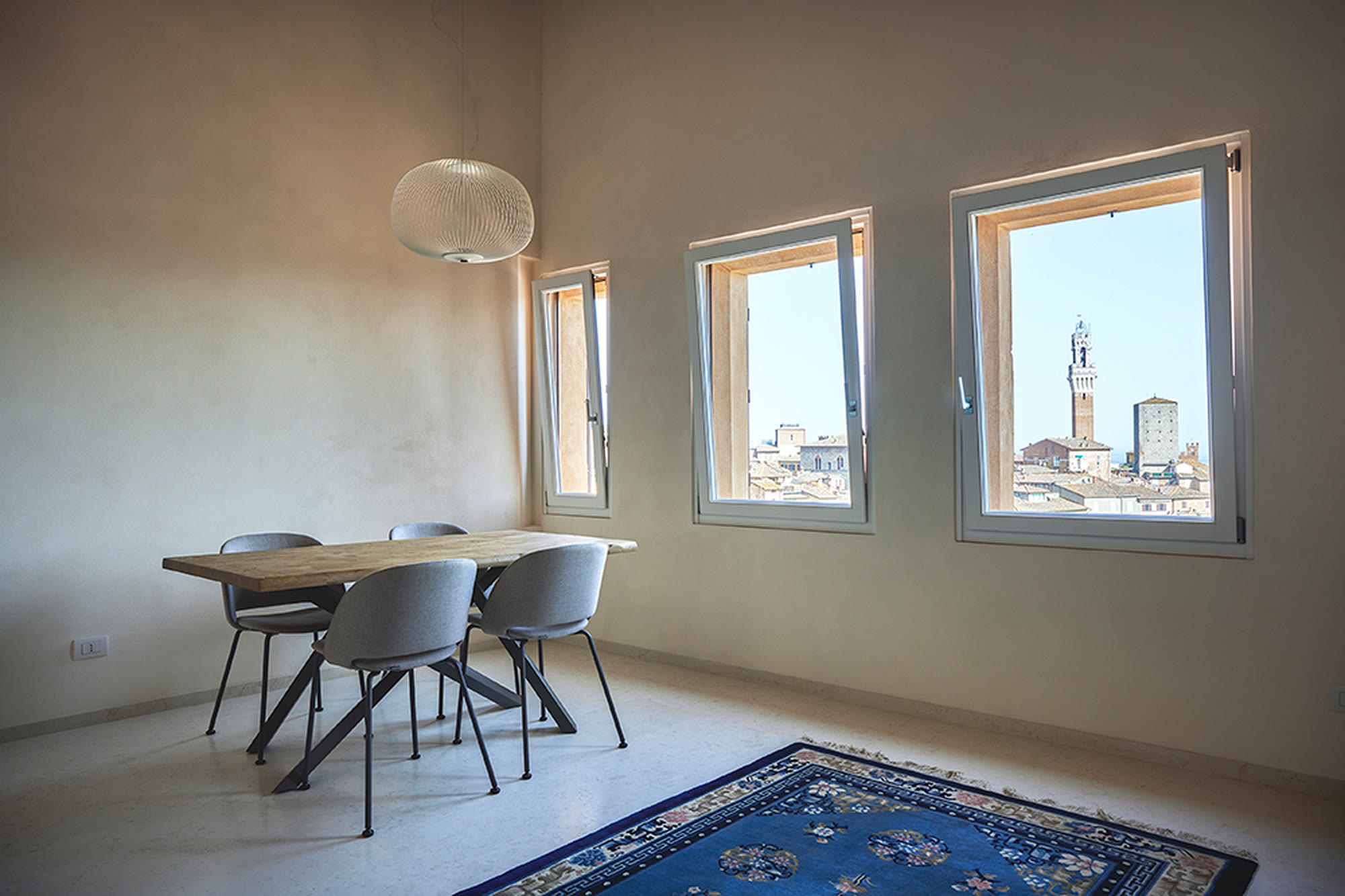Zona pranzo minimale con la Torre del Mangia incorniciata dalle finestre.