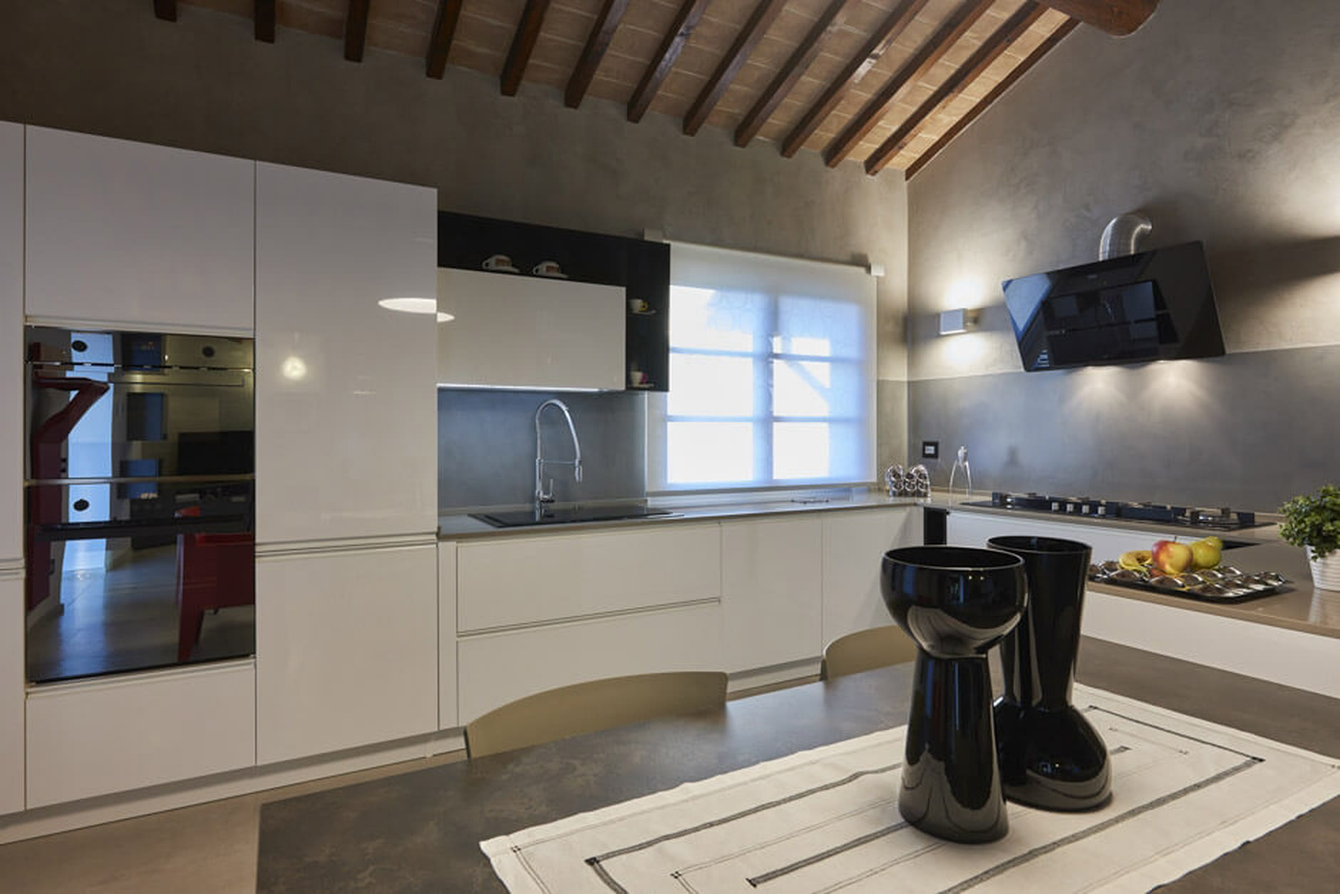 Cucina bianca minimal con penisola chiara e complementi neri.