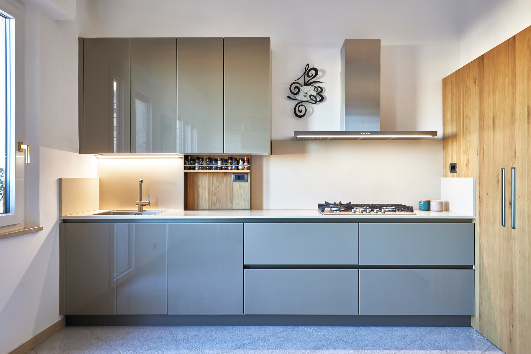 Cucina ad angolo azzurro polvere con piano gas e decoro in ferro battuto a parete.